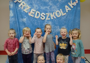 Grupa dzieci uśmiech się do zdjęcia w tle napis dzień przedszkolaka