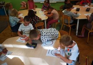 Dzieci przy stolikach kolorują kropki w tle tablica multimedialna