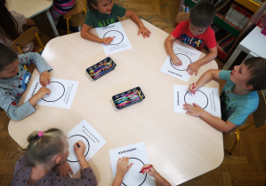 Dzieci przy stolikach kolorują kropki