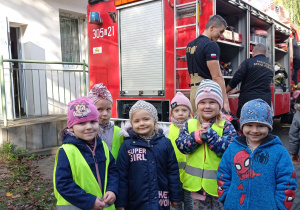 Grupa dzieci pozuje do zdjęcia przed wozem strażackim