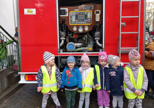 Grupa dzieci pozuje do zdjęcia przed wozem strażackim