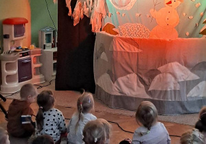 Scenografia do teatrzyku lalkowego, dzieci siedzą na dywanie