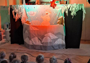 Scenografia do teatrzyku lalkowego, dzieci siedzą na dywanie