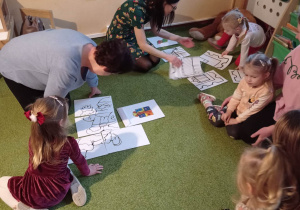 Dzieci z rodzicami układają świąteczne obrazki