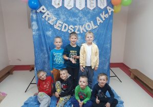 Chłopcy pozują do zdjęcia w tle dekoracja z napisem Dzień Przedszkolaka, balony