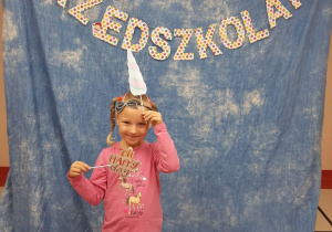 Dziewczynka pozuje na niebieskim tle z napisem "dzień przedszkolaka" i akcesoriami do zdjęć