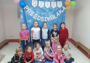 Dziewczynki pozują do zdjęcia w tle dekoracja z napisem Dzień Przedszkolaka, balony