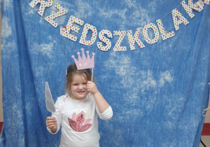 Dziewczynka pozuje na niebieskim tle z napisem "dzień przedszkolaka" i akcesoriami do zdjęć
