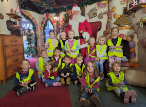 Grupa dzieci pozuje do zdjęcia ze Świętym Mikołajem w scenerii piernikowej chaty Mikołaja