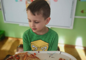 Chłopiec trzyma tace z upieczoną pizzą