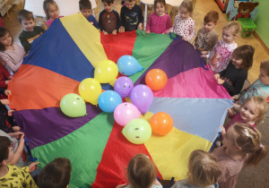 Dzieci bawią się kolorową chustą animacyjną i balonami
