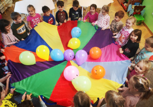 Dzieci bawią się kolorową chustą animacyjną i balonami