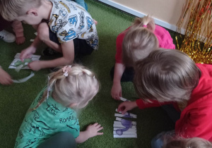 Dzieci układają puzzle z wizerunkiem dinozaura