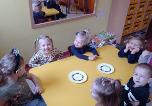 Dzieci przy stoliku obserwują doświadczenie z kolorowymi cukierkami