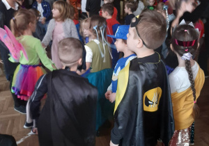Dzieci w strojach karnawałowych tańczą na sali gimnastycznej w szkole