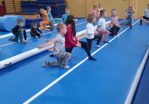 Dzieci skaczą na materacu w tle drabiki w sali gimnastycznej