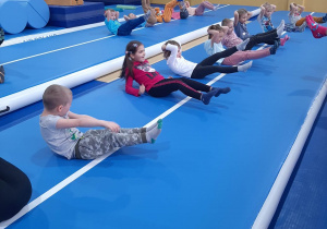 Dzieci wykonują ćwiczenia w leżeniu tyłem na materacach