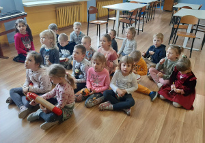 Dzieci siedzą w na podłodze i grają na różnych instrumentach