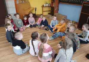 Dzieci siedzą w kręgu na podłodze