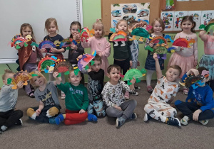 Grupa dzieci pozuje do zdjęcia z dinozaurami wykonanymi z talerzyków papierowych