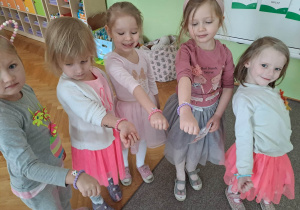 Dziewczynki pokazują do zdjecia bransoletki z koralików