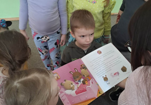 Dzieci z uwagą słuchają jak kobieta czyta ksiażkę