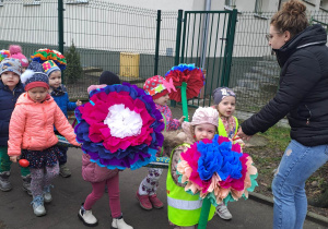 Dzieci maszerują po chodniku w rękach trzymają kwiaty z bibuły