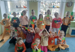 Grupa dzieci pozuje do zdjęcia w rękach trzymają papierowe marchewki