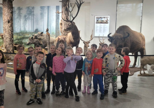 rupa dzieci pozuje do zdjęcia przy eksponatach w muzeum przyrodniczym