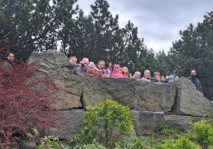 Dzieci machają do zdjecia stojąc na szczycie skały