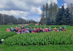 Grupa dzieci robi śmieszne miny do zdjęcia w tulipanach