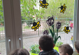 Dzieci wyglądają przez okno i obserwują wronę na drzewie