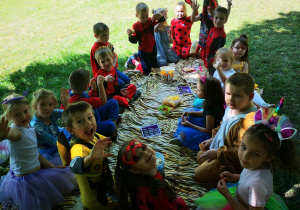 Dzieci siedzą na kocach i jedzą słodycze