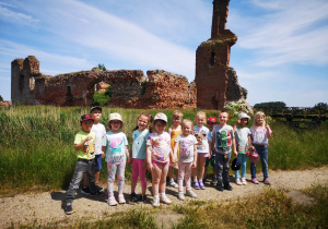 Grupa dzieci pozuje do zdjęcia na tle ruin zamku
