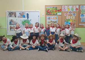 Grupa dzieci w strojach kowbojski i czerwonych bandamkach pozuje do zdjęcia