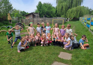 Grupa dzieci pozuje do zdjęcia na zielonej trawie
