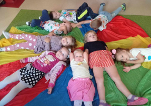 Dzieci leżą na plecach na kolorowej chuście animacyjnej