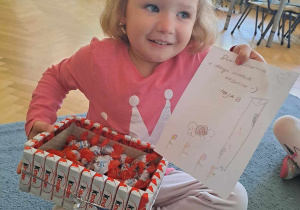 Dziewczynka trzyma pudełko cukierków i rysunek od koleżanki