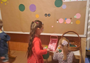 Dzieci przyklejają na tablice kolorowe kropki tworząc wspólnie obraz
