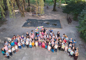 Dzieci w kropkowych strojach pozują do zdjęcia w ogrodzie przedszkolnym