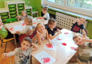 Dzieci przy stoliku wykonują prace plastyczną o tematyce jabłka