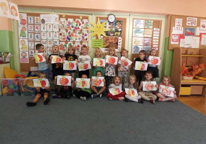Grupa dzieci pozuje do zdjęcia z pracami plastycznymi "Jabłko"