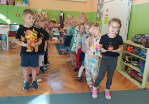 Dzieci wstają w rzędzie i przygotowują się do sztafety z jabłkiem na talerzu