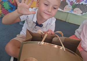 Chłopiec pozuje do zdjęcia z torbą cukierków i pokazuje na palcach ile ma lat