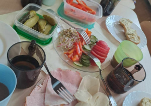 Nakryty stół - talerze, szklanki, owoce, warzywa, szynka, ser