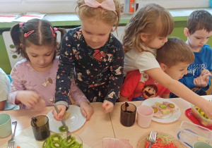 Dzieci samodzielne szykują śniadanie z produktów ustawionych na stole