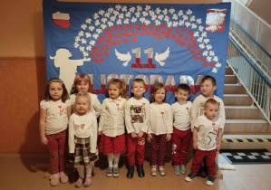 Dzieci ubrane w kolory biało- czerwone pozują na tle dekoracji.