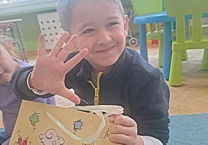 Chłopiec trzyma torbę z cukierkami i pokazuje na palcach ile ma lat
