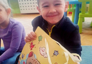 Chłopiec trzyma torbę z cukierkami i uśmiecha się do zdjęcia