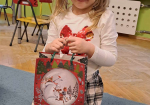 Dziewczynka uśmiecha się do zdjęcia, trzyma w rękach torbę z cukierkami